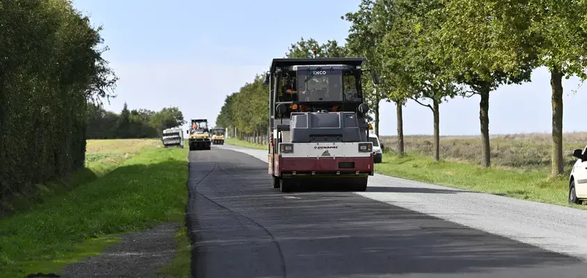 Machine réalisant des travaux d'enrobés sur une route départementale